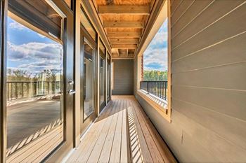 A balcony with wooden flooring and a view of the sky.